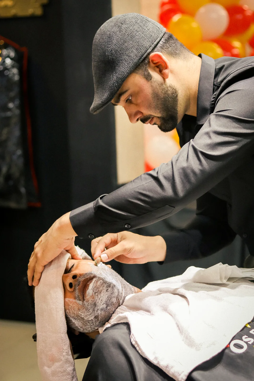 Barbeiro realizando atendimento de barba em cliente reclinado